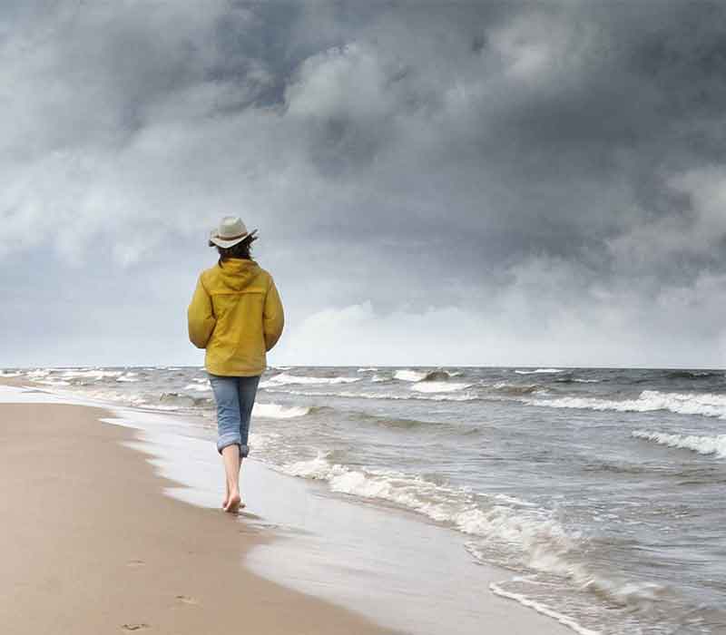 Woman walking on a stormy beach