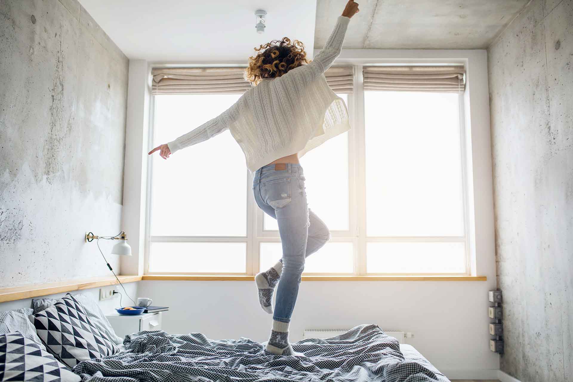 woman dancing on her bed with her back to the camera